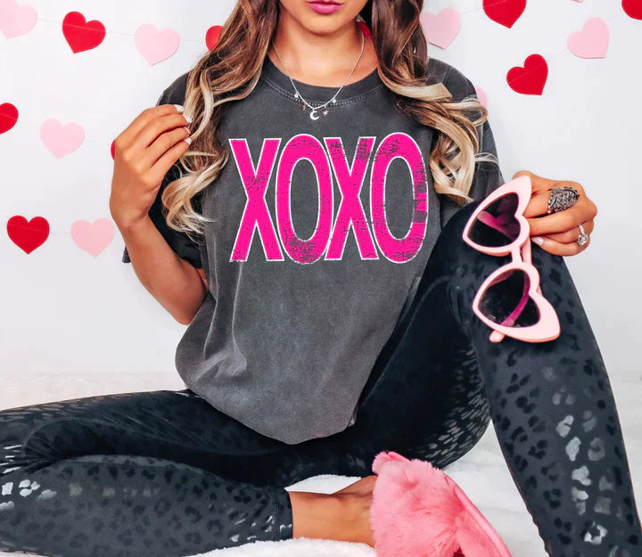 a woman sitting on a bed holding a pair of pink sunglasses