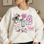 a woman sitting on a bed wearing a white sweatshirt