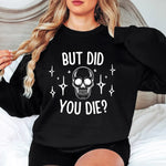 a woman sitting on a bed wearing a black sweatshirt