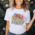 a woman wearing a white t - shirt with flowers on it