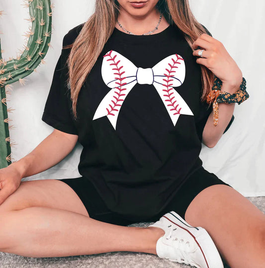a woman sitting on the floor wearing a baseball shirt with a bow