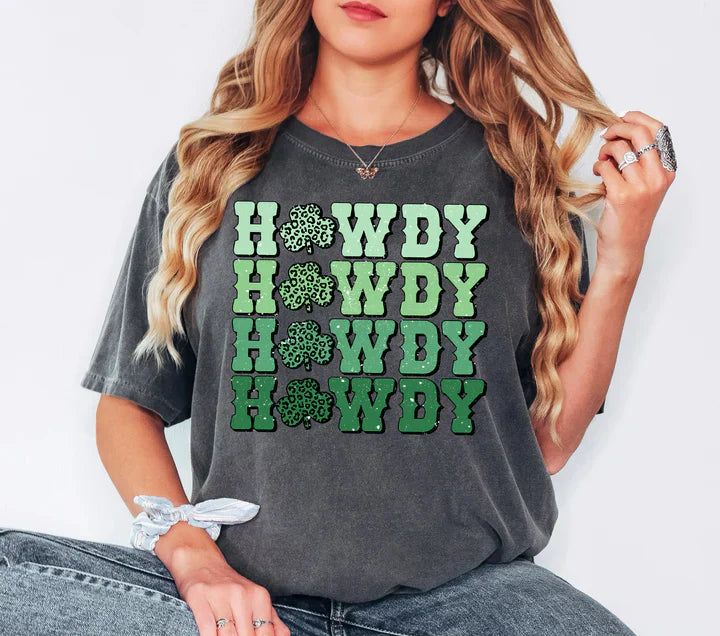 a woman sitting on the ground wearing a gray shirt with green lettering