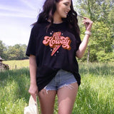 a woman standing in a field with a cowboy hat