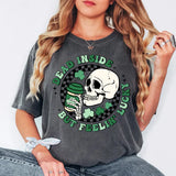 a woman wearing a grey shirt with a skull and shamrocks on it