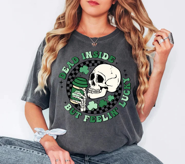 a woman wearing a grey shirt with a skull and shamrocks on it