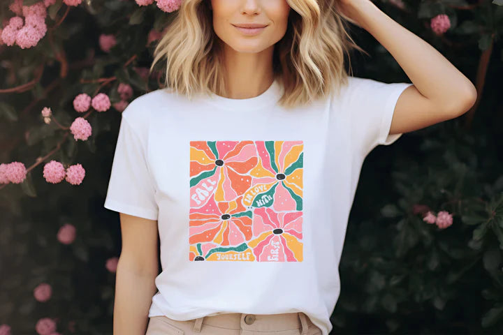 a woman standing in front of a bush with pink flowers