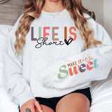 a woman sitting on top of a bed wearing a sweatshirt