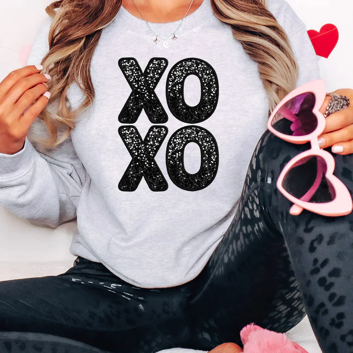 a woman sitting on a bed wearing a sweatshirt and leggings