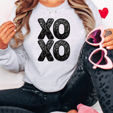 a woman sitting on a bed wearing a sweatshirt and leggings