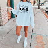 a woman wearing a love sweatshirt and shorts