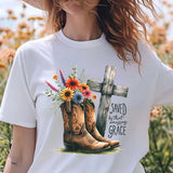 a woman standing in a field of flowers wearing a t - shirt with a cross