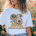 a woman standing in a field of flowers wearing a bloom t - shirt