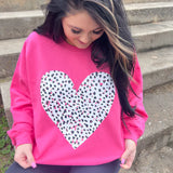 a girl sitting on the steps wearing a pink heart sweatshirt