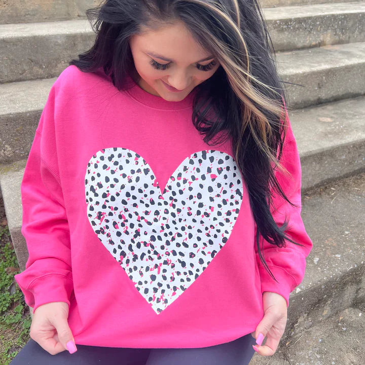 a girl sitting on the steps wearing a pink heart sweatshirt