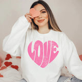 a woman sitting on a bed holding a heart shaped object