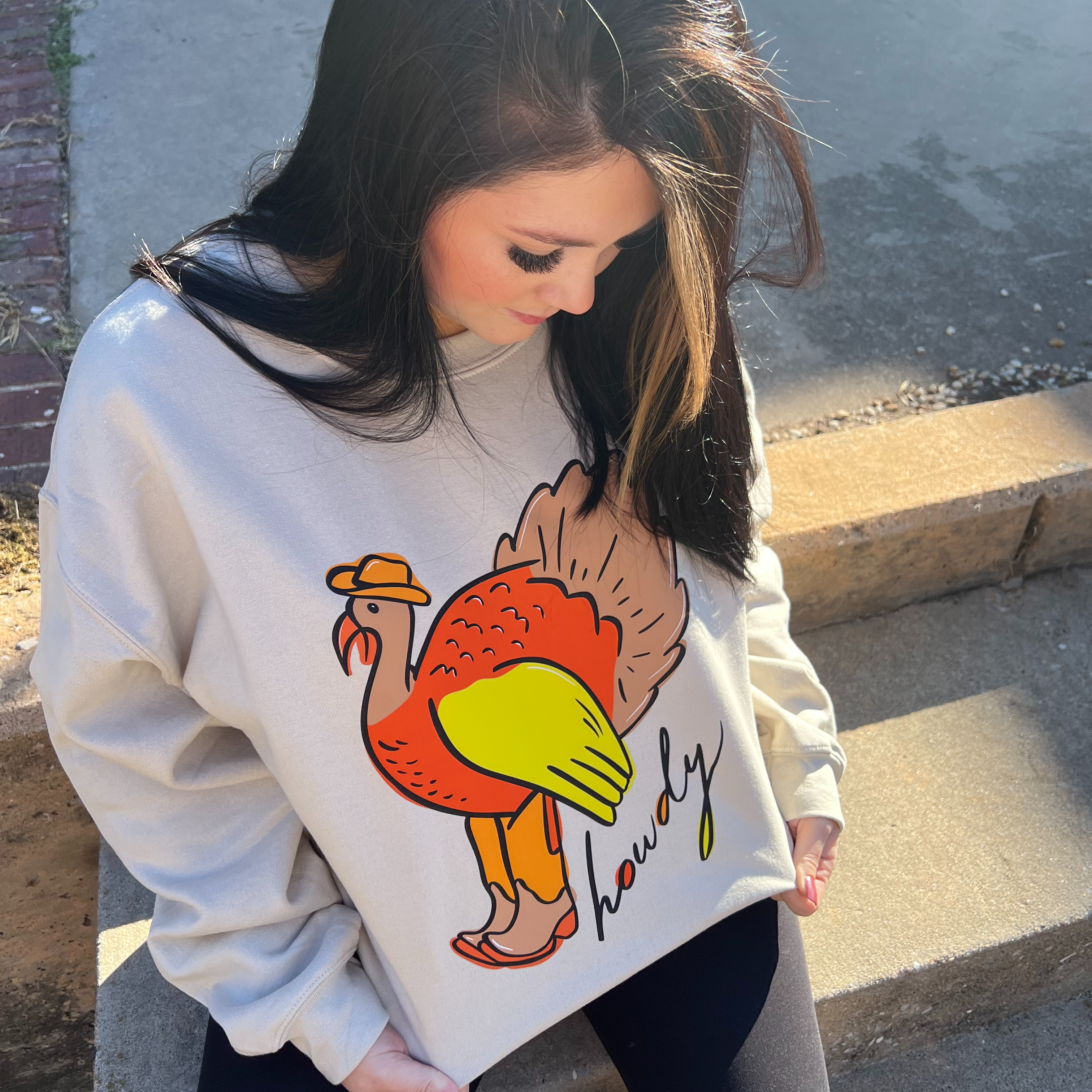 a woman sitting on the steps wearing a sweater with a turkey on it