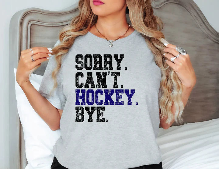 a woman wearing a grey shirt that says sorry can't hockey bye