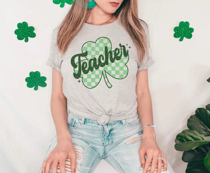 a woman wearing a teacher's t - shirt with a shamrock on it