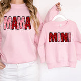 a woman wearing a pink sweatshirt with the word mama printed on it