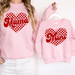 a woman wearing a pink sweatshirt with a matching mom and me heart on it