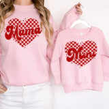 a woman wearing a pink sweatshirt with a matching mom and me heart on it