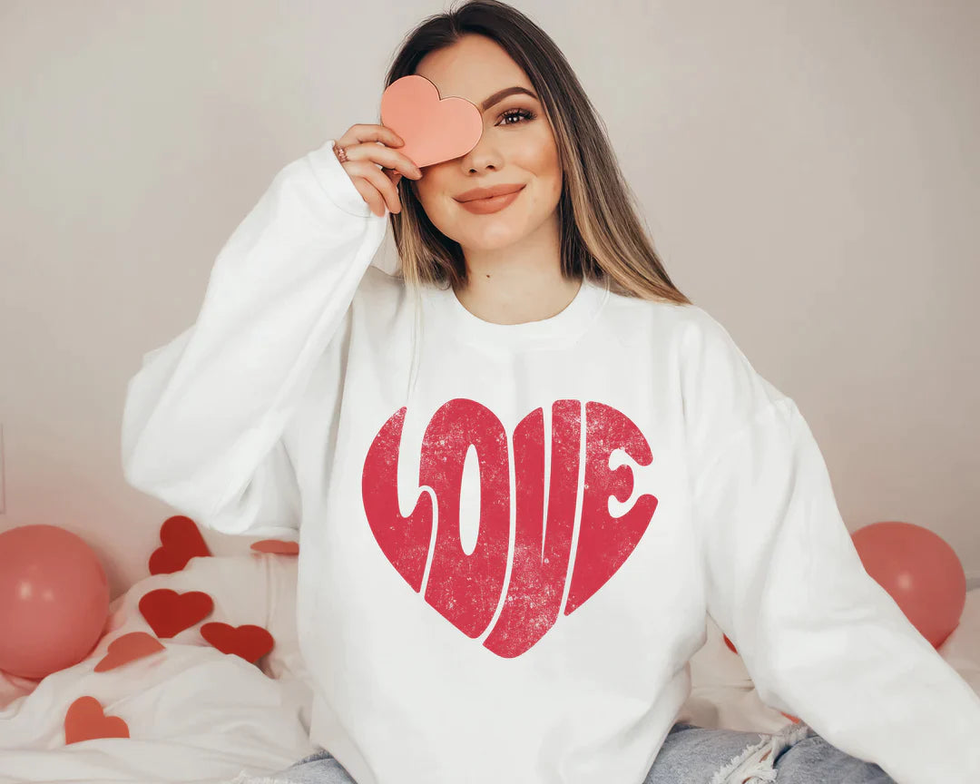a woman sitting on a bed holding a heart shaped object