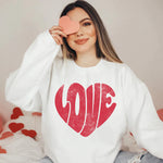 a woman sitting on a bed holding a heart shaped object