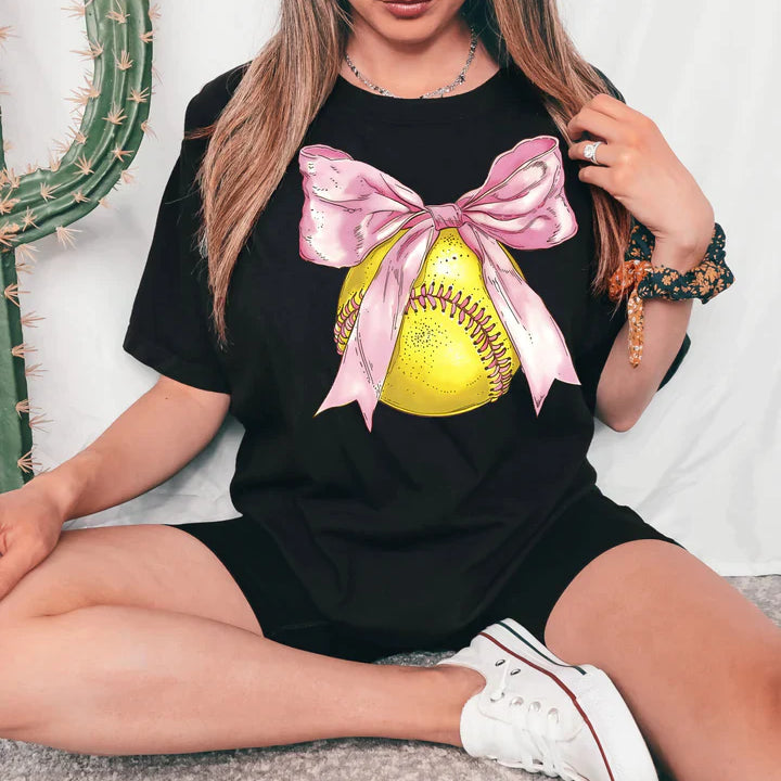 a woman sitting on the floor wearing a t - shirt with a softball on it