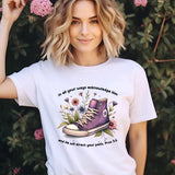 a woman wearing a t - shirt with a pair of shoes on it